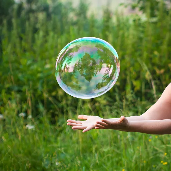 Hand catching a soap bubble