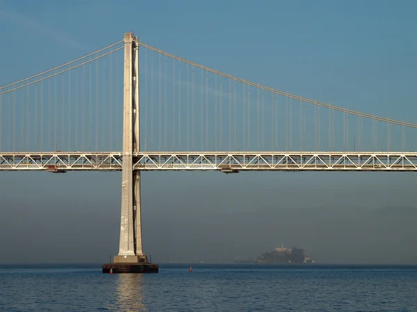 Sun shines on the Bay Bridge with Alcatraz island in the distanc