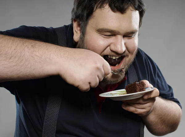 Funny fat guy eating chocolate cake