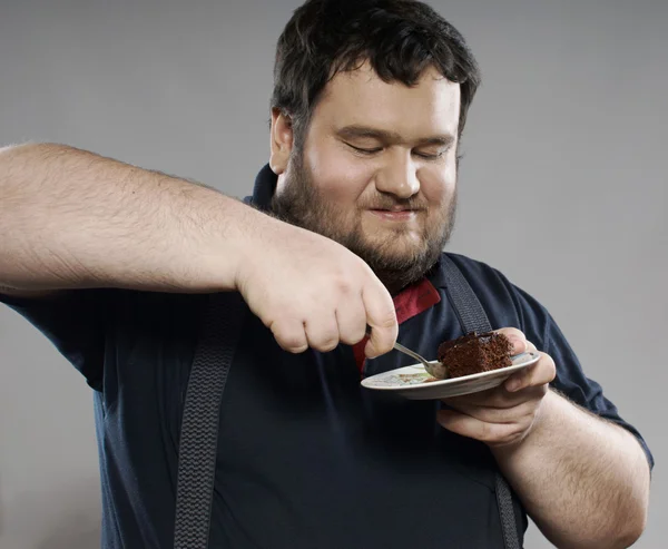 Funny fat guy eating chocolate cake