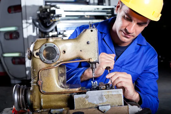 Mechanic repairing industrial sewing machine