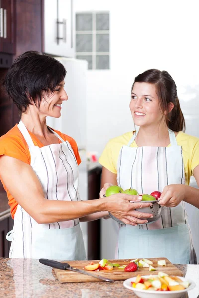 Teen girl helping mother in kitchen