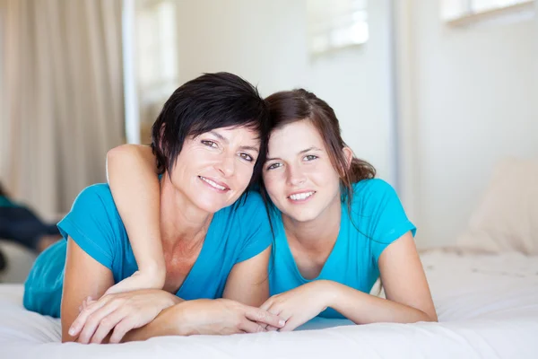 Middle aged mother and teen daughter on bed
