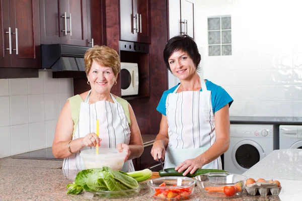 Middle aged woman cooking with senior mother
