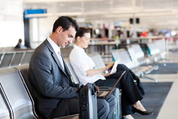 Businessman and businesswoman using computer at airport
