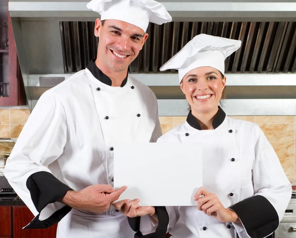 Chefs holding white board in kitchen