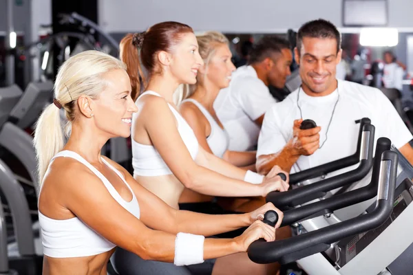 Gym trainer monitoring trainees cycling performance