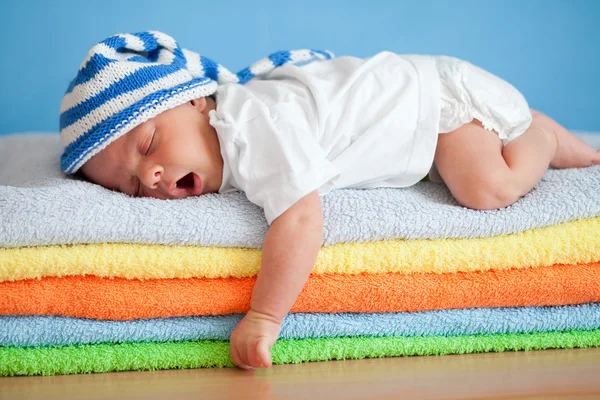yawning sleeping baby on colorful towels stack