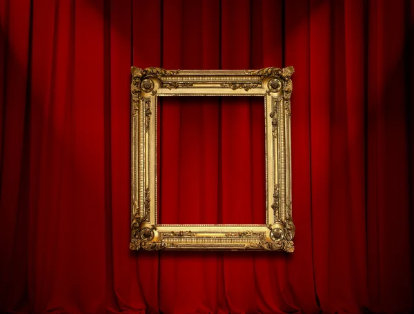 Empty golden painting frame on red curtain wall