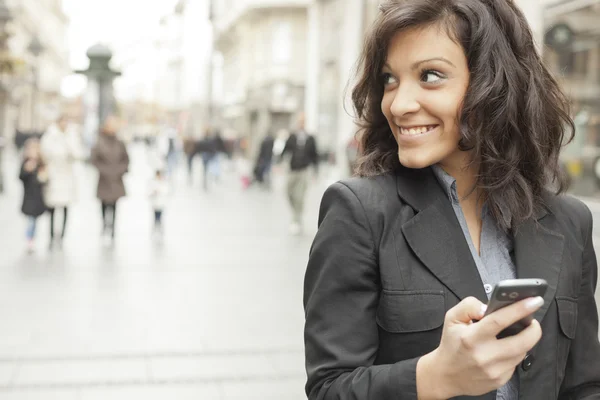 Young Woman with smartphone walking on street