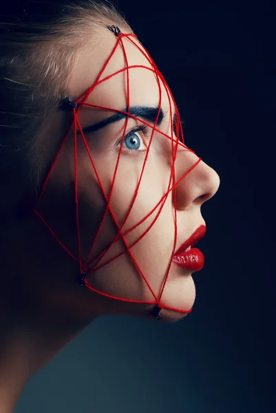 Studio beauty portrait of youg woman with red web on face