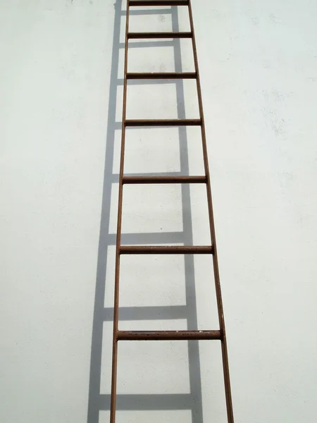 Brown iron ladder on white wall