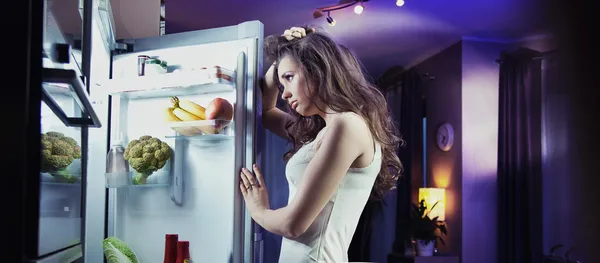 Young woman looking at fridge