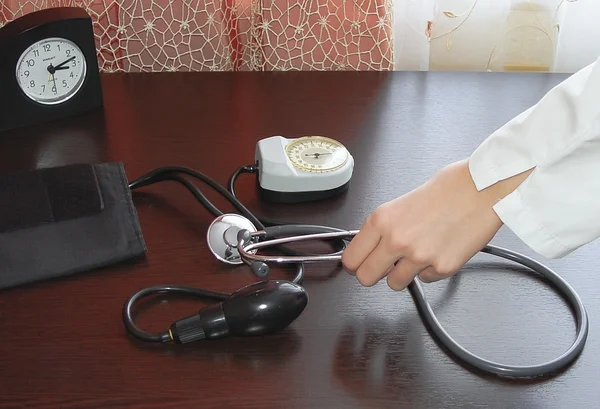 Hand in white coat takes medical blood pressure cuff