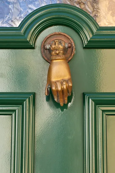 Old knocker in the shape of a hand on a door