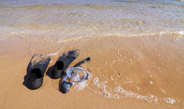 Snorkeling set lying on sand partly in sea water