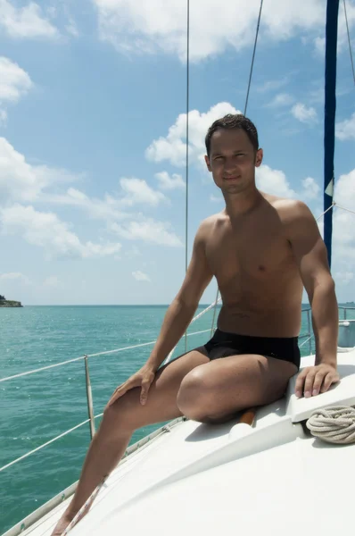 Handsome young adult man sailing on yacht