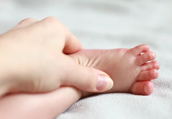 Mother massaging new birth baby foot with love
