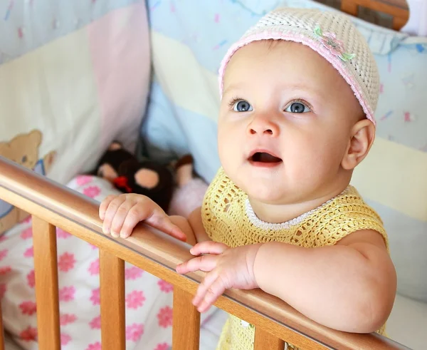 Beautiful funny baby girl with blue eyes looking up standing in