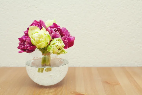 Tied tulips in a glass vase on table and empty space for your te