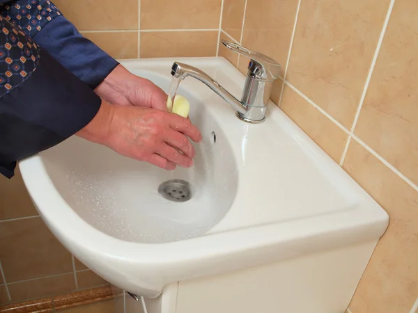 A person washing their hands in the bathroom sink .