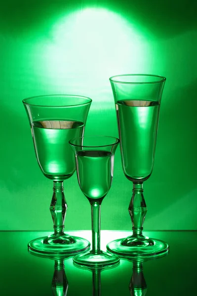 Three wineglasses on the mirror in the green light