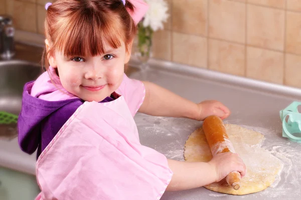 Little girl rolls the dough