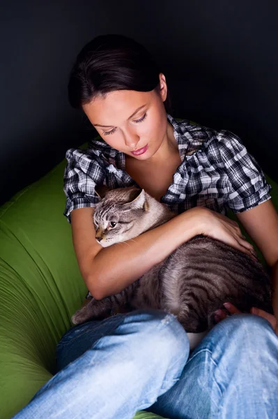 Happy young woman with cat, relaxed on the beanbag couch.