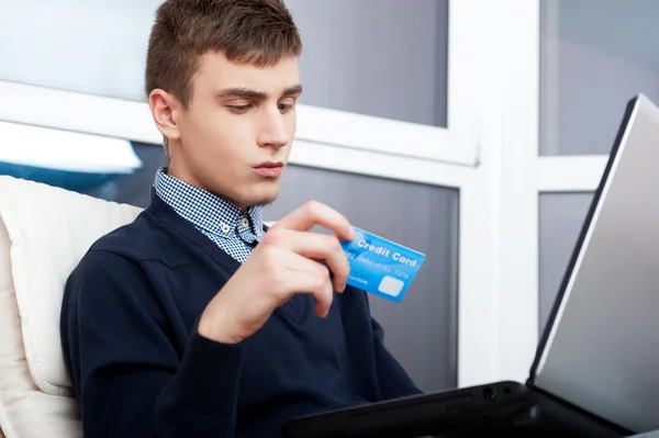 Handsome man holding credit card and using laptop for online sho