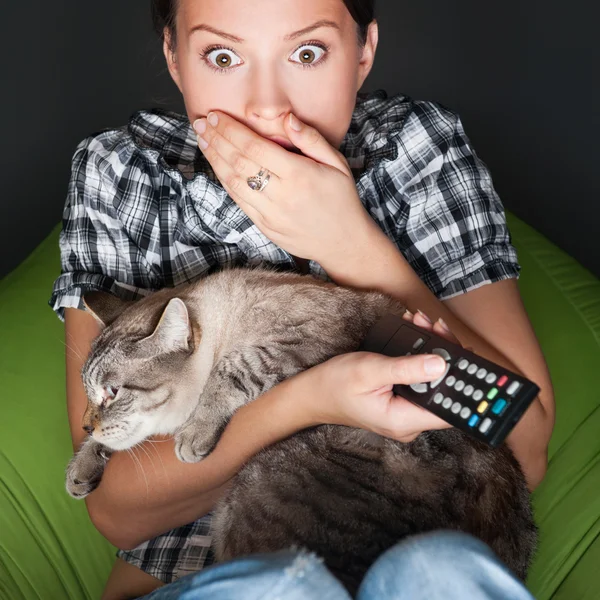 Young funny woman sitting in her beanbag and embracing her cat w