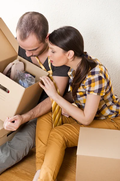 Young Couple with boxes in the new apartment sitting on floor and planning