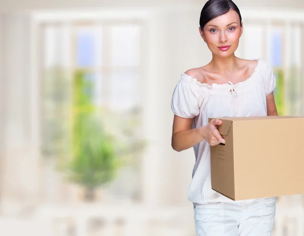 Smiling woman at her home holding boxes. She is moving at her new home. Mortgage concept