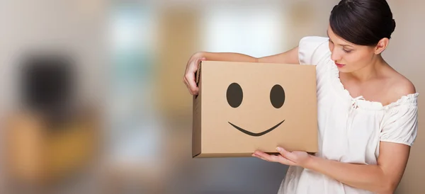 Attractive woman with box making a removal. Smile face illustrated on box. Easy, happy carefree moving concept