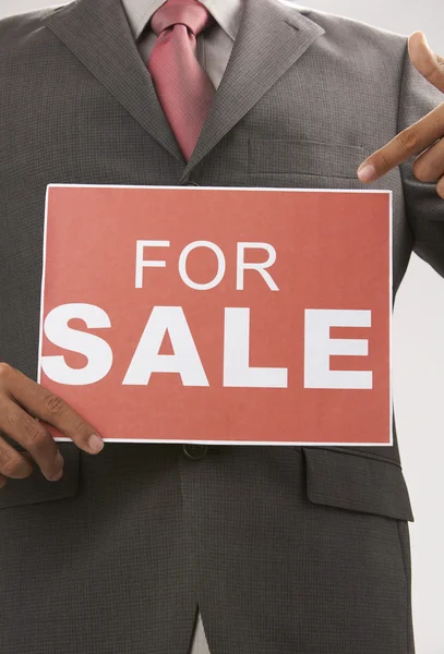 Man holding a for sale signn cover the face