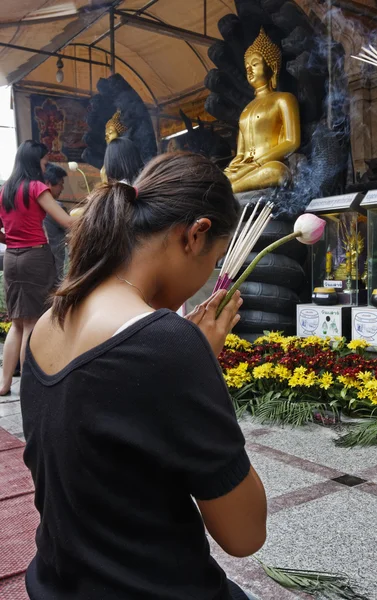 Thailand, Bangkok, Chinatown District, Yaowarat Road, Traimitwitthayaram Temple (Wat Traimit), a Thai girl is praying in front of Buddha statues
