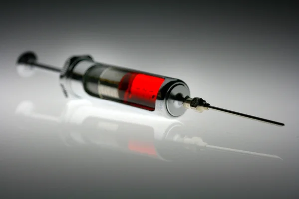Filled syringe against gray background