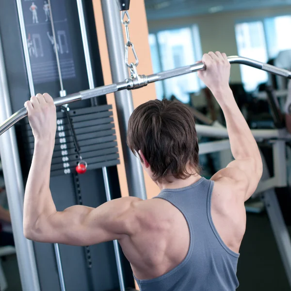 Powerful muscular man lifting weights in gym
