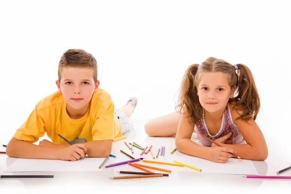 Two children draw with colorful crayons and smile, isolated over