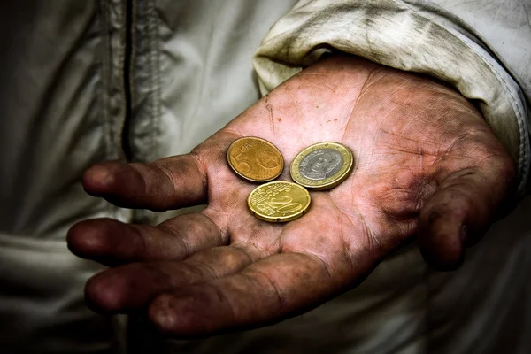 A beggar with some coins on his dirty hands
