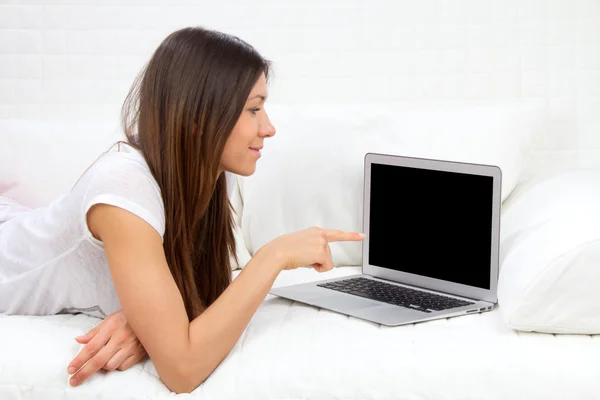 Woman lying on a sofa with laptop paying bills online