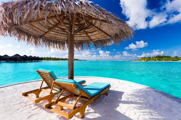 Two chairs and umbrella on tropical beach
