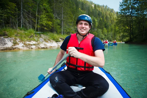 White water rafting - young man in a raft boat, paddling, smili