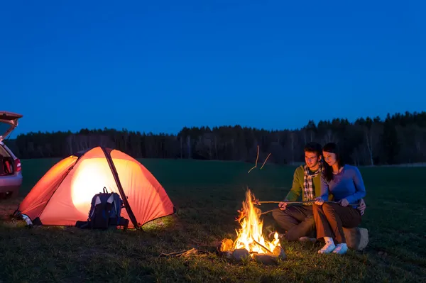Tent camping car couple sitting by bonfire