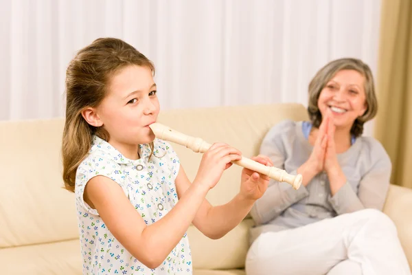 Young girl play flute with proud grandmother