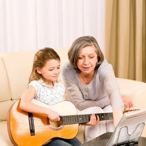Young girl sing play guitar to grandmother