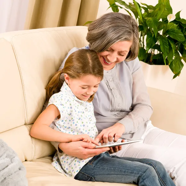 Grandmother with granddaughter use touch tablet