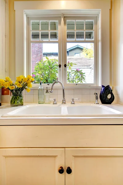 Kitchen sink and white cabinet with window.
