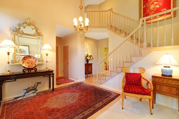 Luxury entrance living room with red rug, staircase.