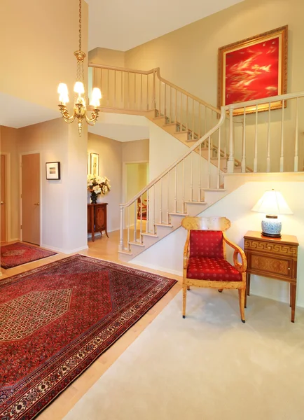 Luxury entrance living room with red rug, staircase.