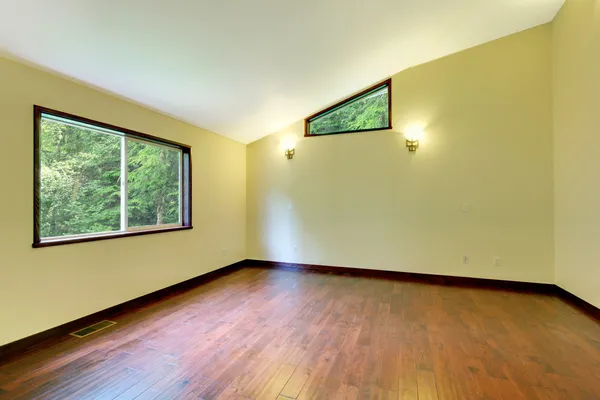 Large yellow empty room with large window and wood floor